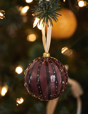 Joelle paper mache ornament hanging on a christmas tree branch