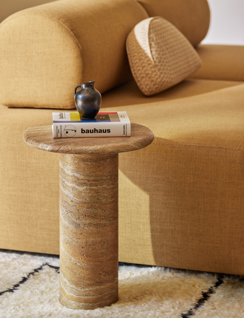 #color::faux-canyon-travertine | Mona round stone drink table styled next to a modular armless sofa.