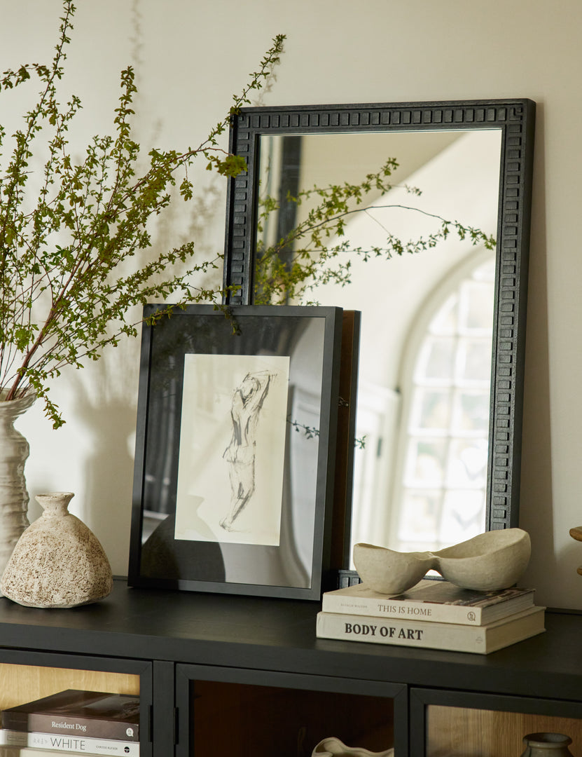 #color::black | Thelma black carved wood framed mirror styled with a framed print and ceramic vases on top of a black console cabinet