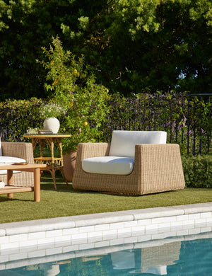 Aisha wide arm modern wicker outdoor swivel chair in a poolside lounge.