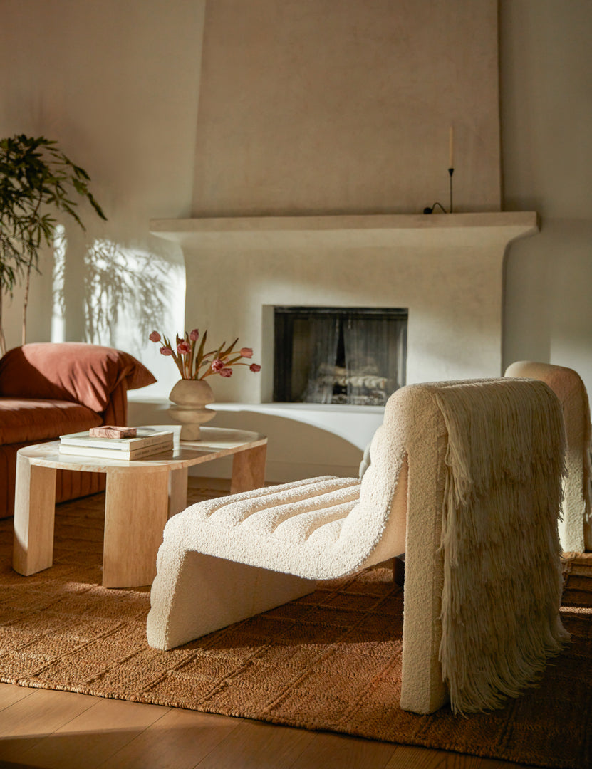 #color::ivory-boucle | Leon textural boucle channel tufted armless accent chair by Carly Cushnie styled with an oval stone coffee table.