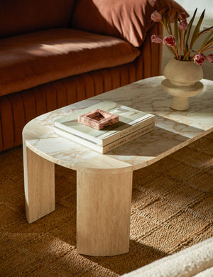 Mahoe oval marble and travertine coffee table by Carly Cushnie styled with a sculptural vase and square marble catchall tray.