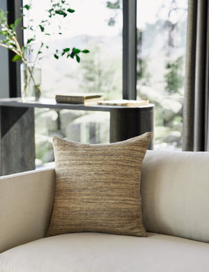 The Bryce natural-toned silk square pillow sits natural linen sofa in a room with floor to ceiling windows