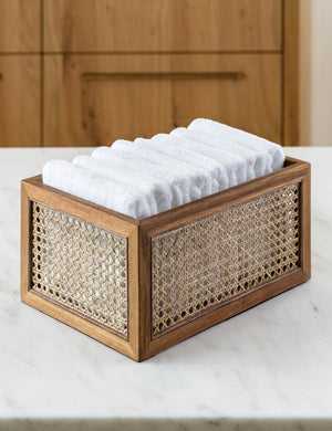 Rattan cane bin by NEAT Method sits on a marble countertop with white towels