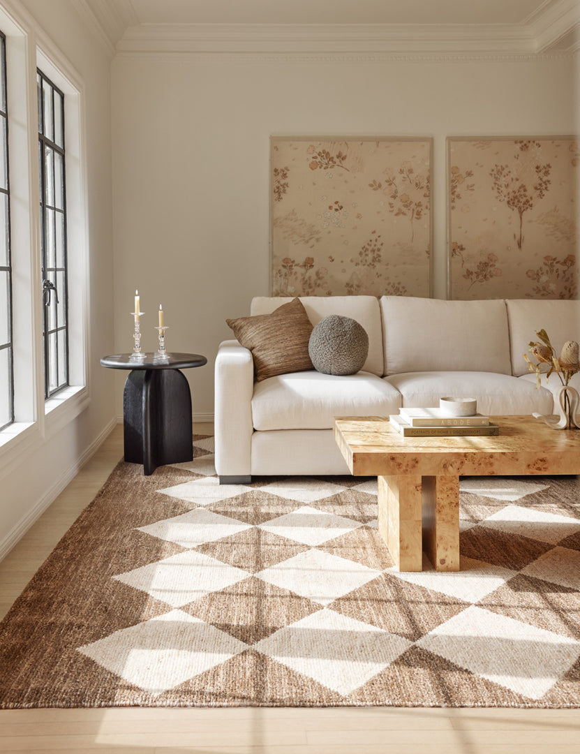 #color::white | Cera Beeswax Column Candles in white sit in two glass candle holders in a living room with a cream couch and a rug with a diamond pattern