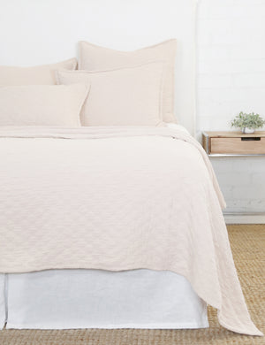 Ojai Cotton Matelasse Blush Pink Euro Sham by Pom Pom at Home sits on a white framed bed with other Ojaj blush pink linens