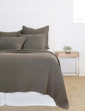 Ojai Cotton Matelasse Pebble Gray Euro Sham by Pom Pom at Home sits on a white framed bed with other Ojaj pebble gray linens