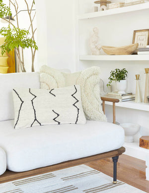 The moroccan black and natural beni ourain inspired lumbar flat weave pillow by Sarah Sherman Samuel sits atop a white linen sofa