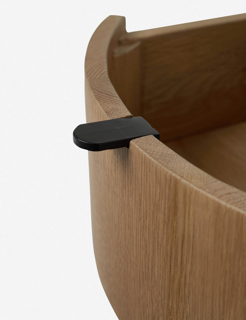 | Close-up of the black tab drawer pull with the drawer opened on the Kono round solid oak nightstand with one drawer